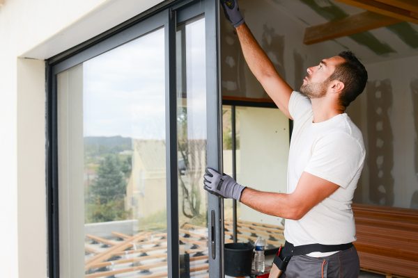 handsome young man installing bay window in a new house construction site